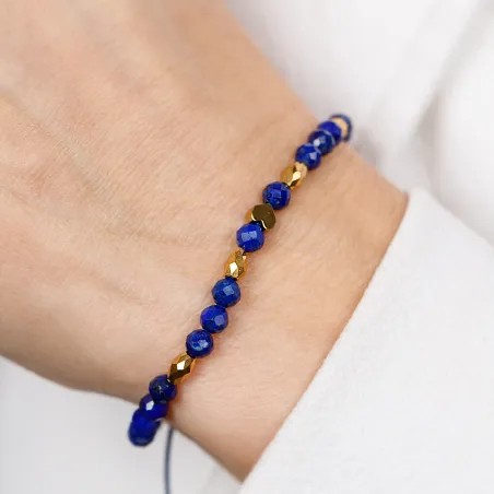 Bransoletka na granatowym sznurku z fasetowanymi kulkami lapis lazuli i złotymi wielościanami na nadgarstku